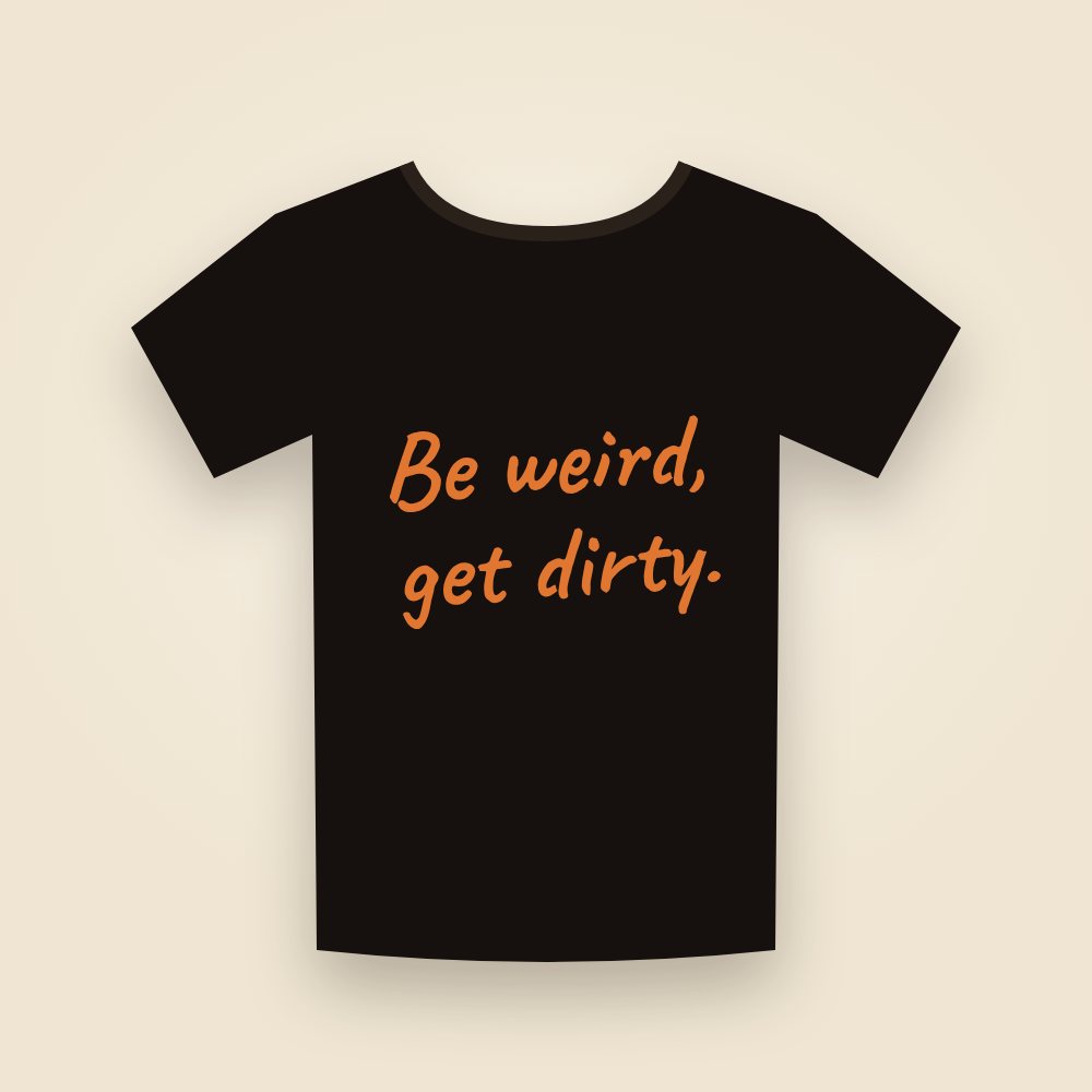 A black T-shirt with "Be weird, get dirty." in orange handwriting across the chest.